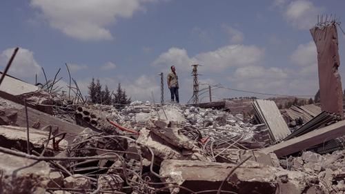 Человек на фоне разрушенного израильским ударом здания, город Набатия, южный Ливан.